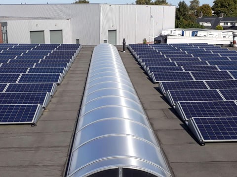 Moderne gebogen lichtstraten op een industrieel dak, harmonieus geïntegreerd tussen zonnepanelen