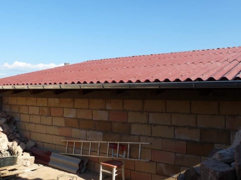 Vers gelegd dak van rode golfplaten van vezelcement, bouwplaats op de voorgrond