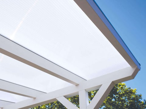 Elegante witte dubbelwandige lichtplaten op een moderne terrasoverkapping weerkaatsen het zonlicht en zorgen voor een lichte, vriendelijke buitenruimte