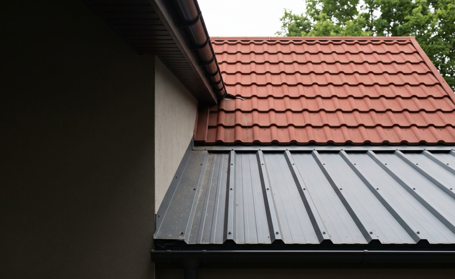 Roodbruine dakpanplaten op het huisdak en antracietkleurige damwandplaten op de aanbouw