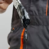 Verfkwast met zwarte vloeibare kunststof die van de borstels druipt, detailopname