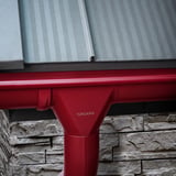 Detail van kersrode Niagara dakgoot en regenpijp met logo op een stenen muur