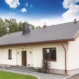 Volledig huis met koperbruine Niagara dakgoten en regenpijpen, witte gevel en donker dak