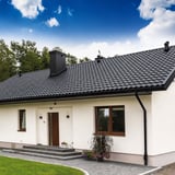 Witte woning met gitzwarte (RAL 9005) Niagara stalen dakgoten en regenpijpen