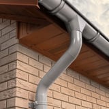 Niagara dakgoot en regenpijp in grijs aluminiumkleurig (RAL9007) gemonteerd aan een bakstenen muur