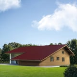 Dakpanplaat Wijnrood (RAL 3005) op het dak van een houten huis, installatie in zonlicht