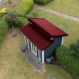 Dakpanplaat Wijnrood (RAL 3005) op het dak van een tuinhuis, bovenaanzicht van de installatie