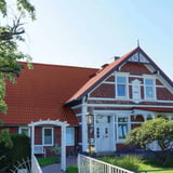 Dakpanplaat aluminium 0,70 mm roodbruin op het dak van een historisch bakstenen huis