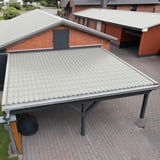 Dakpanplaat Grijswit RAL 9002 op het dak van een carport voor een bakstenen huis