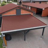 Dakpanplaat aluminium Roodbruin RAL 8012 op een carportdak, op de achtergrond andere gebouwen met dezelfde dakbedekking