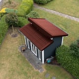 Dakpanplaat aluminium Roodbruin RAL 8012 op het lessenaarsdak van een modern tuinhuis, vogelperspectief