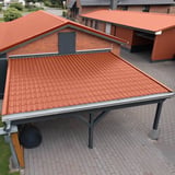 Dakpanplaat 2/1060 Koperbruin op het dak van een carport en aangrenzende gebouwen