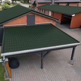 Carport met mosgroen dakpanplaat-dak voor een bakstenen huis