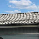 Dakoppervlak met Grijswit (RAL 9002) dakpanplaat EUROPA en dakgoten, blauwe lucht