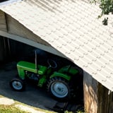 Dakpanplaat EUROPA Zuiverwit op een schuurdak met groene tractor eronder