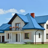 Huis met dak van dakpanplaat Szafir 350/15 in Gentiaanblauw, met balkon en witte gevel