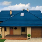 Vooraanzicht van een huis met dak van dakpanplaat Szafir 350/15 in Gentiaanblauw en dakraam