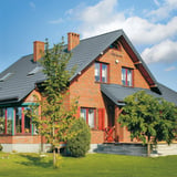 Bakstenen huis met dak van dakpanplaat Szafir 350/15 Pelsgrijs, 0,50 mm