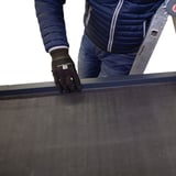 Montage van het antracietgrijze dakrandprofiel CUBE op een plat dak, persoon met handschoenen