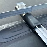 Dak reparatieband, wit, rond een metalen rail op een donker dak geplaatst