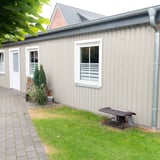 Zijaanzicht van een gebouw met damwandplaat 20/1100 Grijswit (RAL 9002) aan de wand