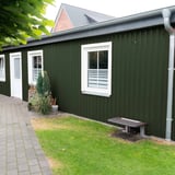 Damwandplaat 20/1100 wand chroomoxide groen als bekleding van een aanbouw met witte ramen en regenpijp