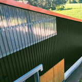 Damwandplaat 20/1100 wand mosgroen als gevel van een hal, gecombineerd met transparante lichtplaten