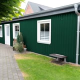 Damwandplaat 20/1100 wand mosgroen als gevel van een aanbouw met witte ramen en dakgoot