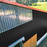Gitzwarte damwandplaat 20/1100 als gevelbekleding met lichtplaten op een hal