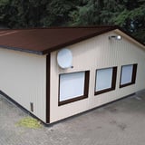 Damwandplaat 35/207, Chocoladebruin, als dak op een licht gebouw met satellietschotel