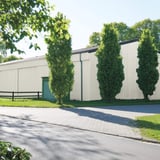 Damwandplaat 35/207 Wand, Grijswit, als gevelbekleding van een grote opslaghal met groene poort