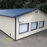 Damwandplaat 35/207 Wand, Grijswit, als gevel van een klein gebouw met donker dak en ramen
