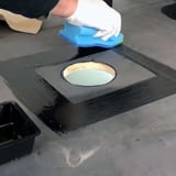 Montage EPDM activering: Hand met witte handschoen brengt zwarte oplosmiddel aan rondom ronde afvoer