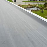 Geplaatste zwarte EPDM dakfolie op een plat dak met witte dakrand
