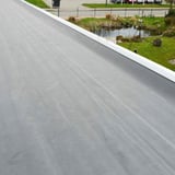 Gelegde zwarte EPDM dakfolie 1,20 mm op een plat dak met witte dakrandafwerking
