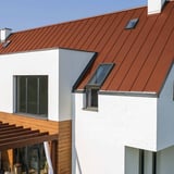 Staande felsplaat PD-510-S trapezium Terracotta op een dak met dakramen en witte gevel
