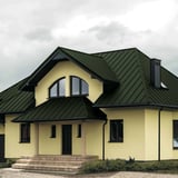 Staande naad dakpan PD-510-S trapezium Chroomoxydegroen op een woonhuis met dakkapellen en schoorsteen