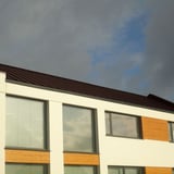 Staande felsplaat PD-510-S trapezium Chocoladebruin op een modern gebouw met grote ramen