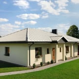 Gelijkvloers huis met dak van staande felsplaat PD-510-S Micro in zuiverwit, met schoorsteen