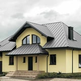 Staande felsplaat PD-510-S Micro, lichtgrijs, op een huis met gele gevel en dakkapellen
