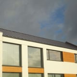 Modern gebouw met grijs aluminiumkleurig felsdak PD-510-S Micro onder bewolkte hemel