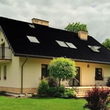Felsplaat PD-510-S Gitzwart RAL 9005 op een dak van een huis met dakramen en schoorstenen