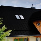 Felsplaat PD-510-S Gitzwart RAL 9005 op een dak van een huis met twee dakramen