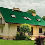 Huis met mintgroen felsdak PD-510-S, met meerdere dakramen en schoorstenen