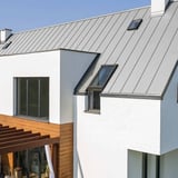 Modern wit huis met staande felsplaat PD-510-S Lichtgrijs (RAL 7035) dak en dakramen