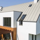 Dak met felsplaat PD-510-S in Grijswit, 0,50 mm, op een wit huis met dakramen
