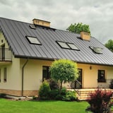 Felsplaat PD-510-S Zilver-Metallic op een woonhuis met meerdere dakramen en schoorsteen