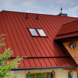 Felsdakpaneel PD-510-S Vlak Koraalrood op een woonhuis met houten gevel