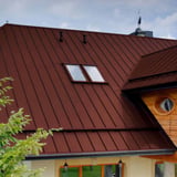 Close-up van een Roodbruin Stehfalzdach PD-510-S met twee dakramen en houten bekleding