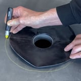 Handen markeren met gele stift de omtrek van de zwarte EPDM garantie-gully op een dakbaan